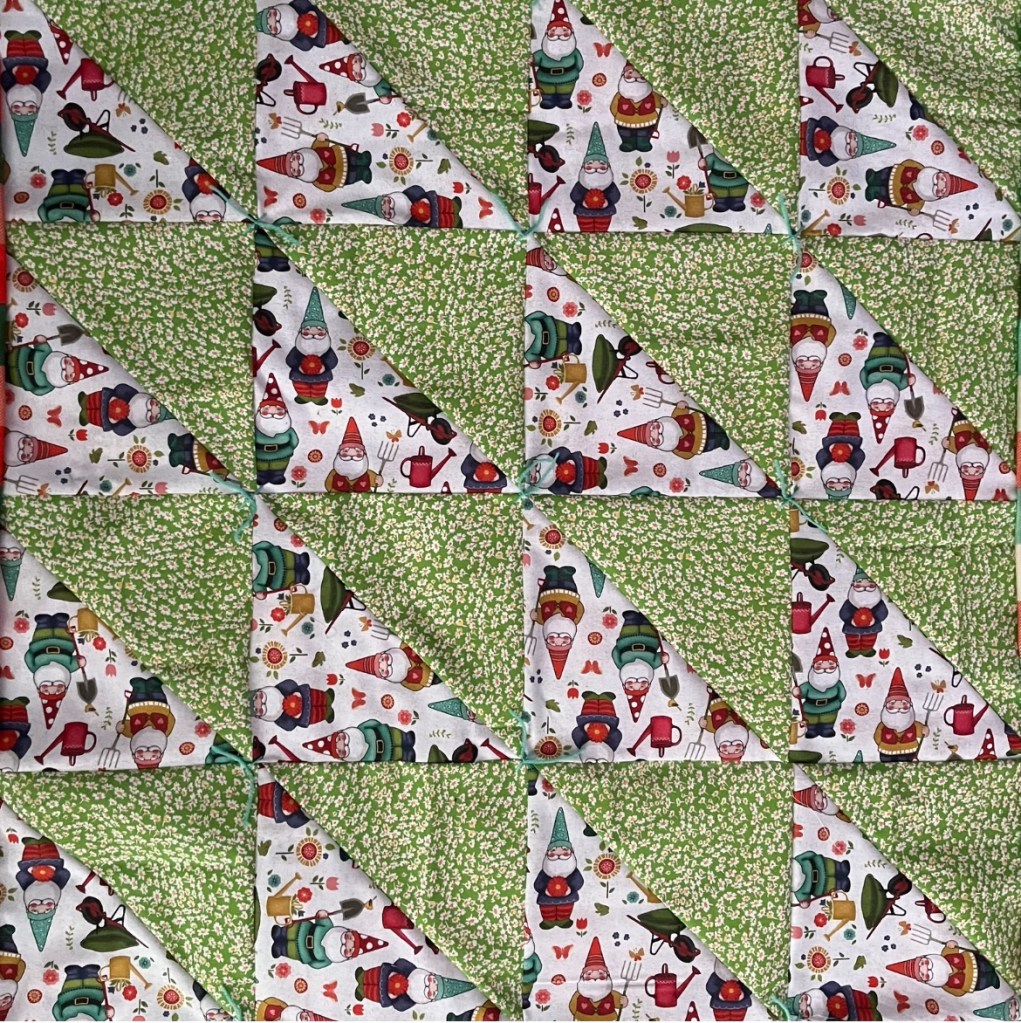 Quilt with right triangles in a green floral print and a gnome print