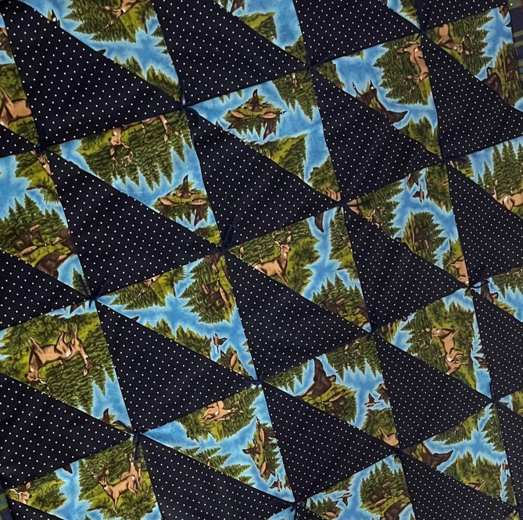 Quilt with right triangles in navy polka dot print and forest scene print