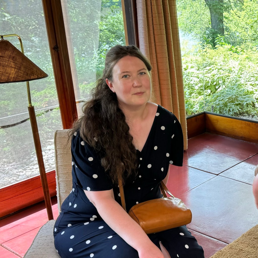 Alex in a navy polka dot dress sitting in a Frank Lloyd Wright house